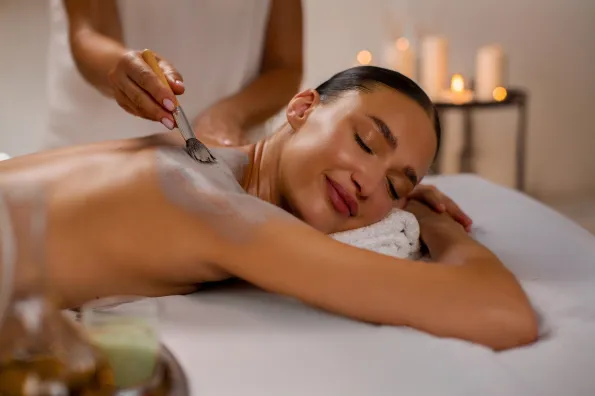 woman relaxing on massage table with clay mask on her back.