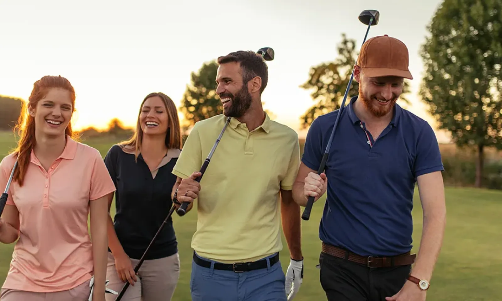 A group of men and women walking and laughing on a golf course 