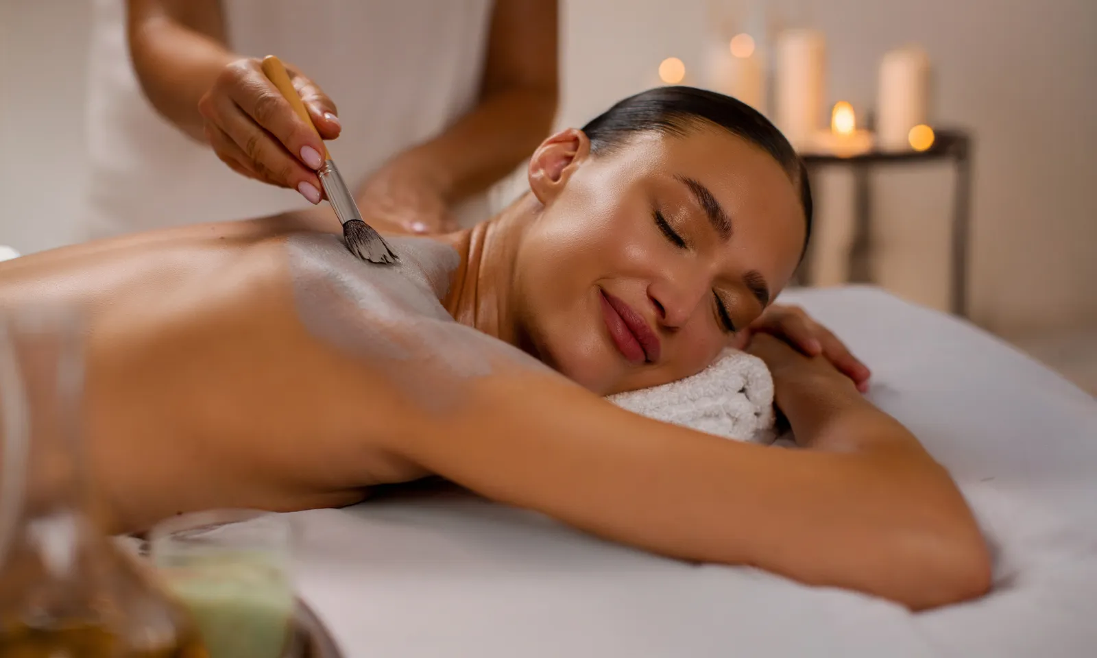 woman relaxing on massage table with clay mask on her back.